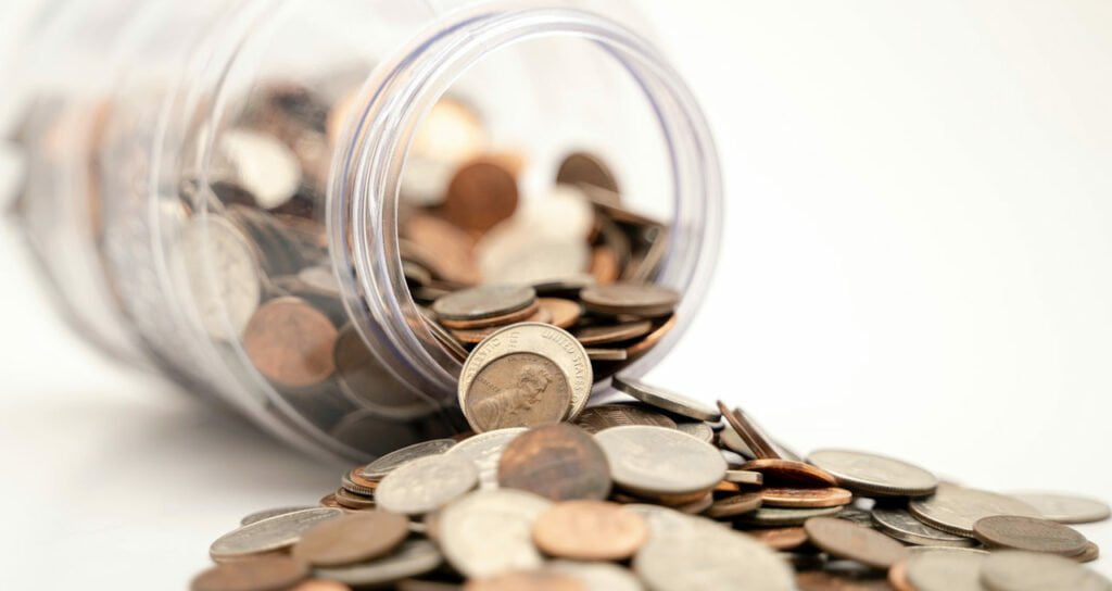 pote de vidro com moedas que representam a economia que um cartão premiação pode trazer a uma empresa