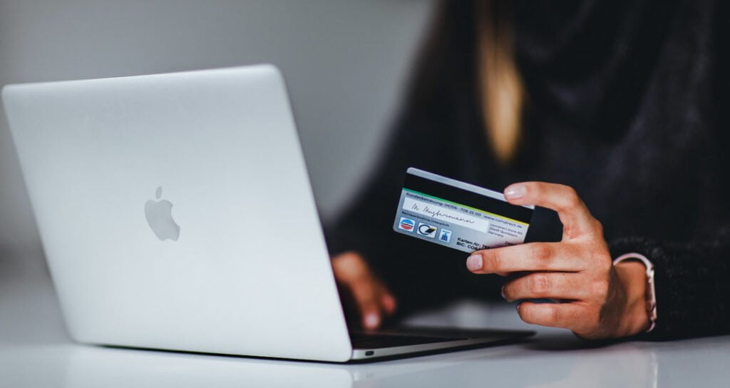 mulher utilizando cartão de crédito para comprar em loja online