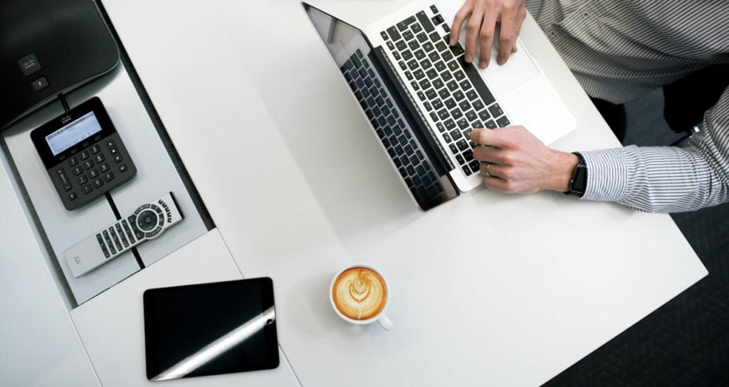 homem trabalhando no computador com café e praticidade